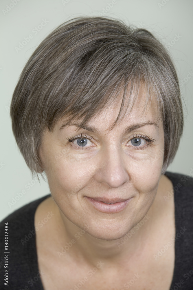 Closeup portrait of beautiful middle age woman smiling against colored background Closeup portrait of beautiful middle age woman smiling against colored background