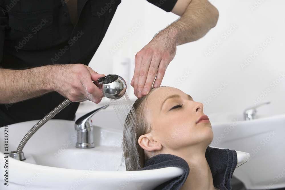 Closeup of young woman getting hair wash from hairdresser in salon Closeup of young woman getting hair wash from hairdresser in salon