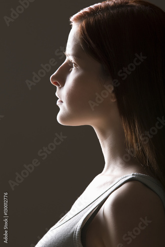 Closeup side view of serious young woman over black background