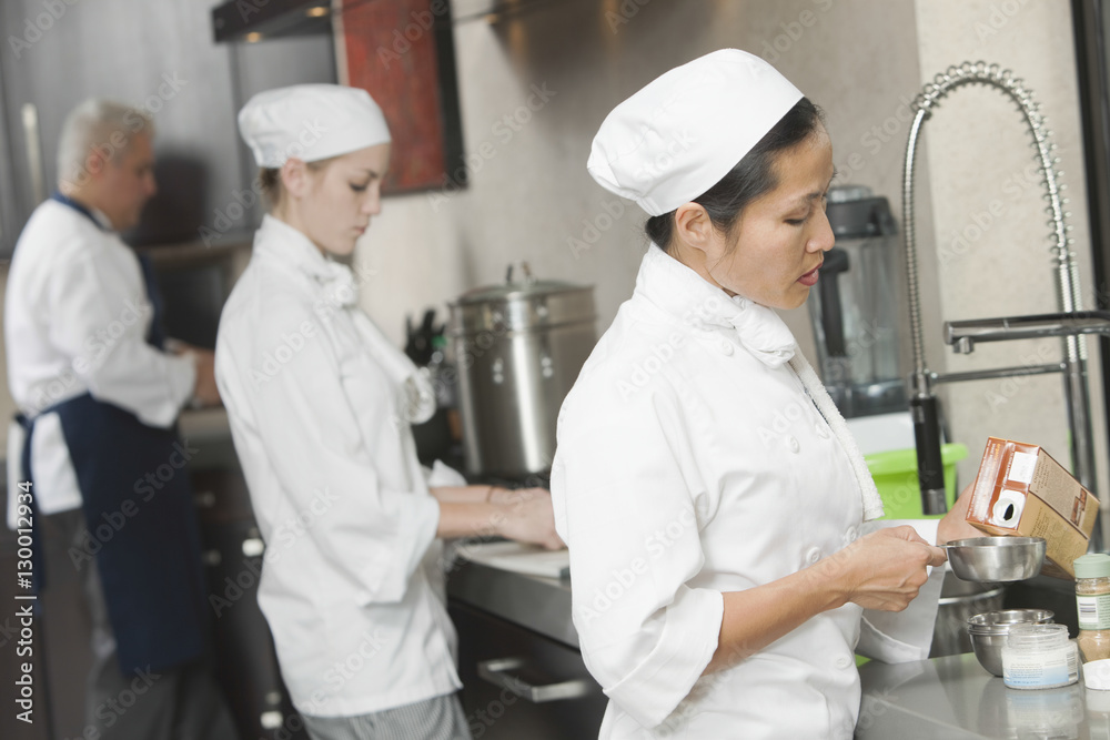 Fotografie Three chefs working side by side in busy commercial kitchen