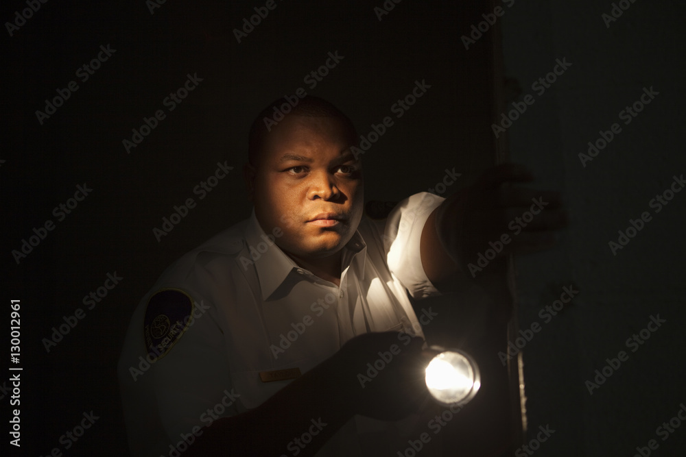 Closeup of young mixed race security guard investing with torch light Stock  Photo | Adobe Stock