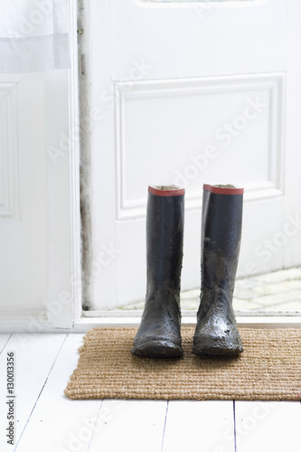 Muddy wellington boots on door mat