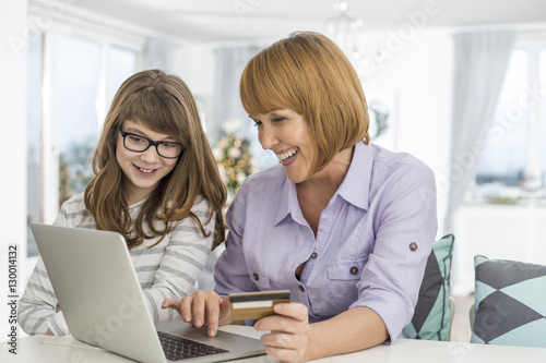 Cheerful mother and daughter shopping online at home during Christmas