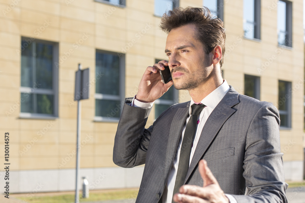 Young businessman conversing on cell phone against office building Young businessman conversing on cell phone against office building