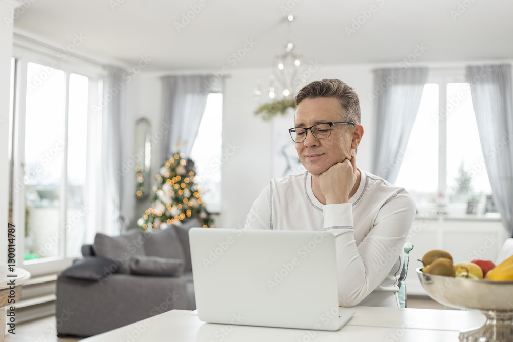 Smiling man using laptop at home Smiling man using laptop at home