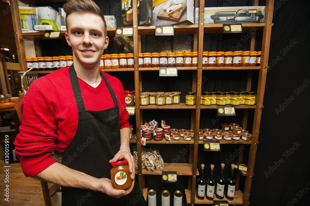 Obraz premium Portrait of smiling salesperson holding jar in supermarket