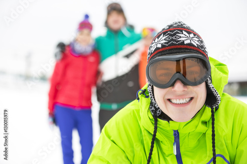 Portrait of smiling young man with friends in background during winter