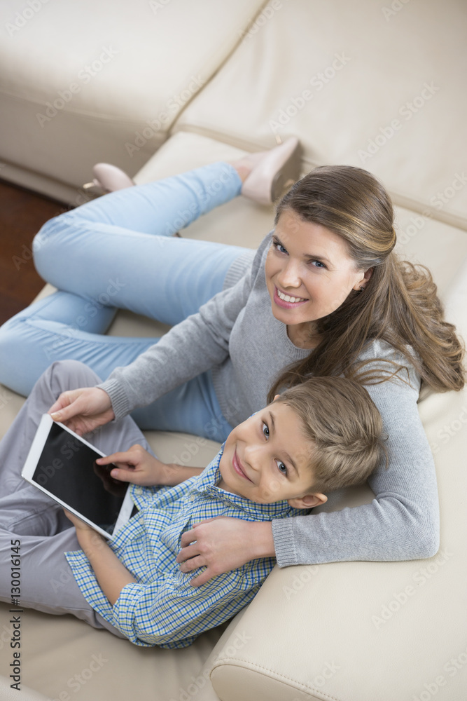 High angle portrait of mother and son with tablet PC sitting on sofa High angle portrait of mother and son with tablet PC sitting on sofa