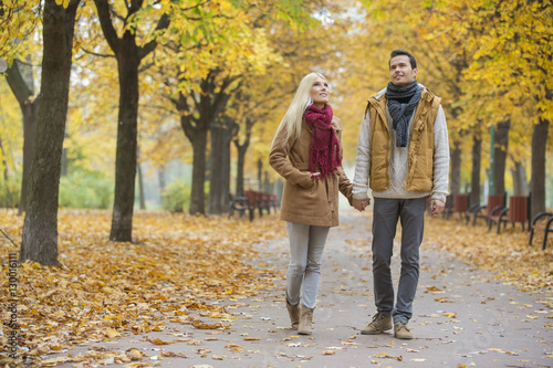 Full length of couple walking while looking up in park during autumn © moodboard