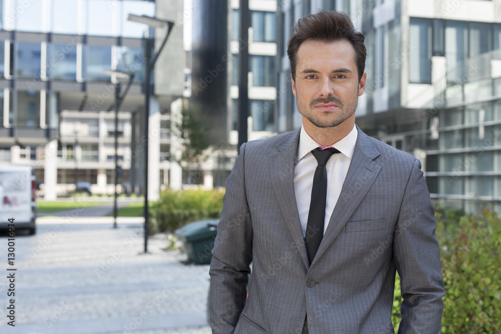 Portrait of confident young businessman standing outside office building Portrait of confident young businessman standing outside office building