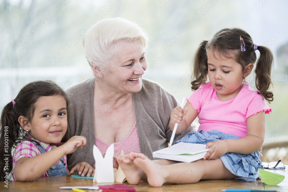Happy senior woman with granddaughters making handicraft at home Happy senior woman with granddaughters making handicraft at home