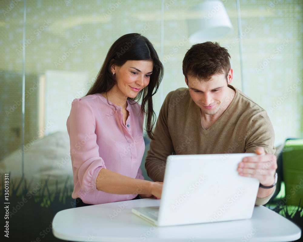 Young businessman and businesswoman using laptop at office table Young businessman and businesswoman using laptop at office table