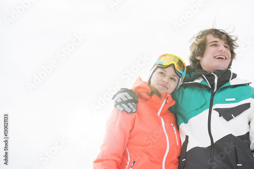 Loving young couple in warm clothing against clear sky