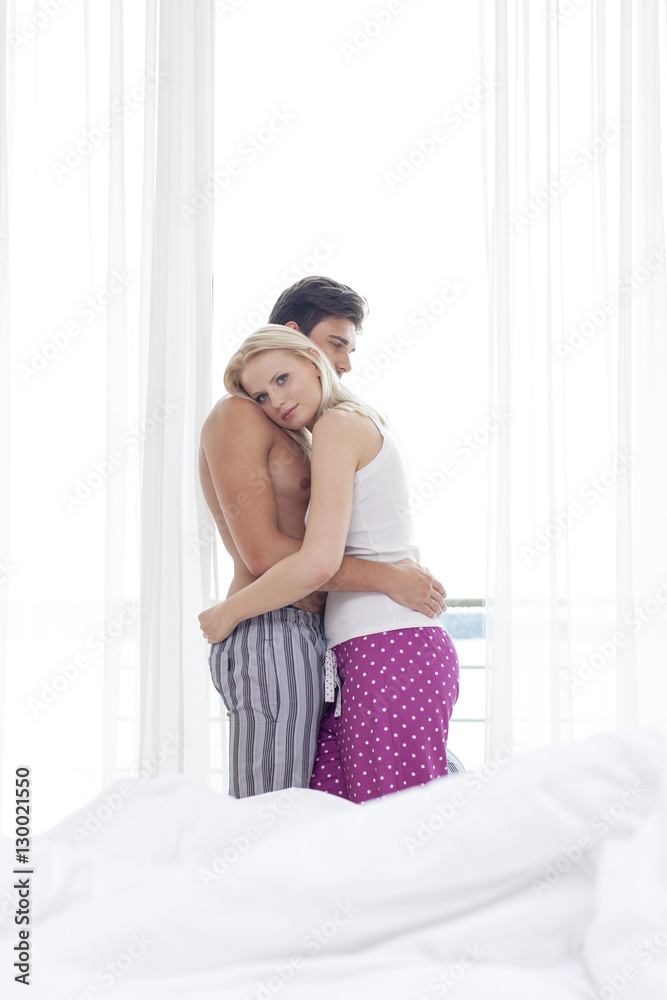 Side view of young couple hugging in hotel room Side view of young couple hugging in hotel room