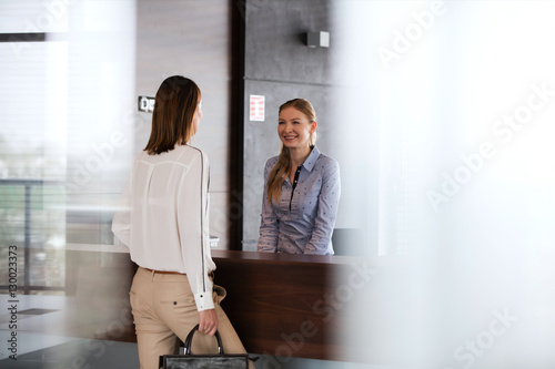 Foto Happy young receptionist talking with businesswoman in office