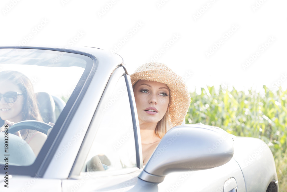 Woman sitting in convertible with female friend on sunny day
