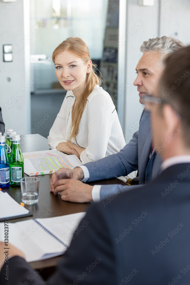 Fototapeta premium Portrait of young businesswoman sitting with male colleagues in conference room