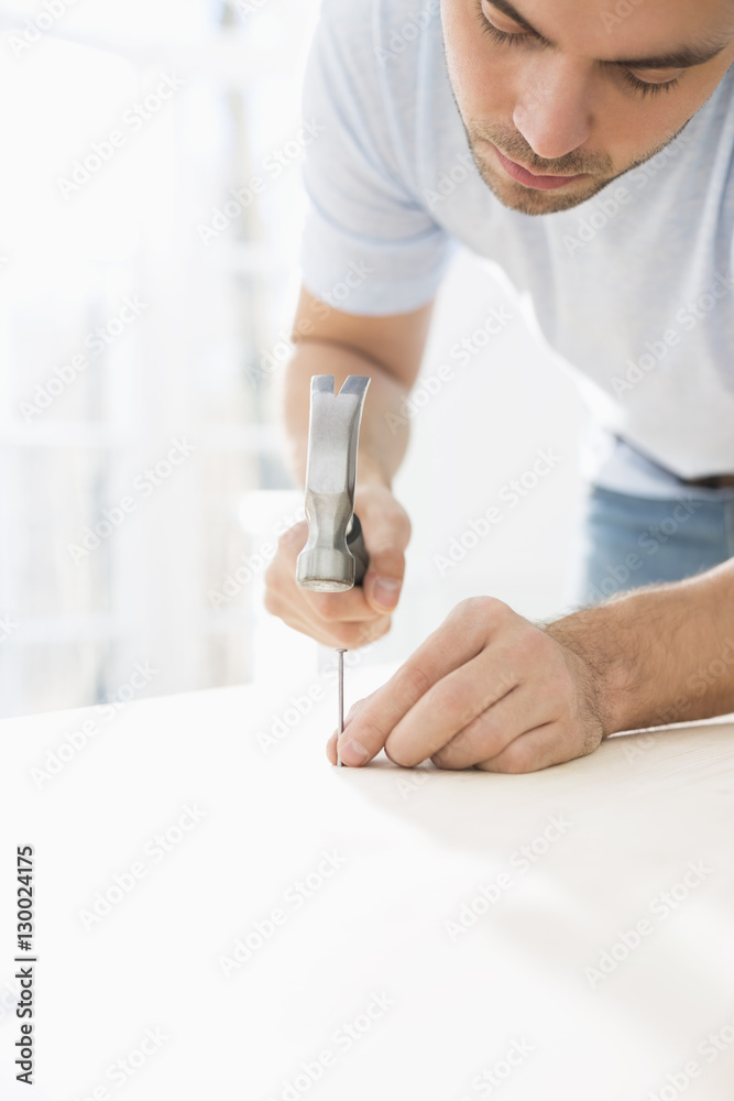 Mid-adult man nailing in table Mid-adult man nailing in table