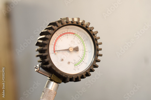 Industrial manometer pressure gauge isolated on a white background. Air compressor gun manometer with black needle and color scale for psi or bar.