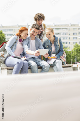 Young students photographing themselves through digital tablet at campus