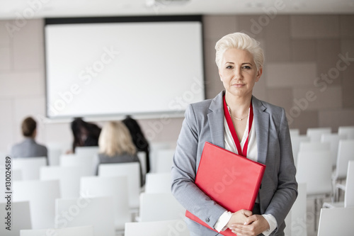 Portrait of confident businesswoman holding file in seminar hall