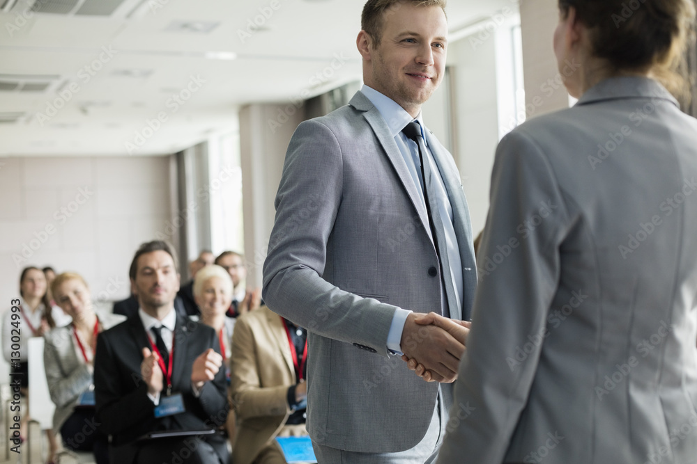 Confident businessman greeting public speaker during seminar Confident businessman greeting public speaker during seminar