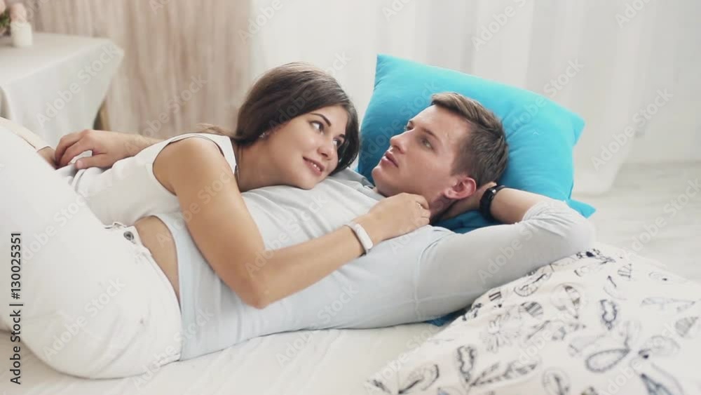 Cute couple cuddling and talking on bed Stock Video | Adobe Stock