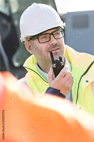 Confident supervisor using walkie-talkie at construction site