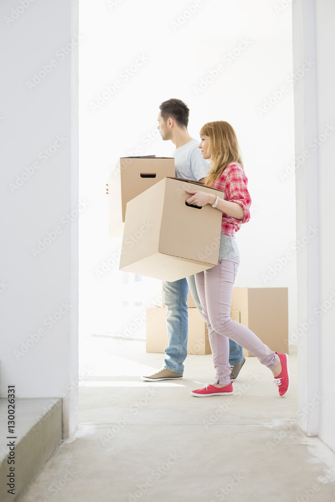 Full-length side view of couple walking with cardboard boxes Full-length side view of couple walking with cardboard boxes