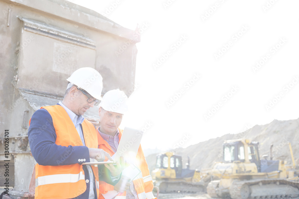 Engineers using laptop at construction site against clear sky