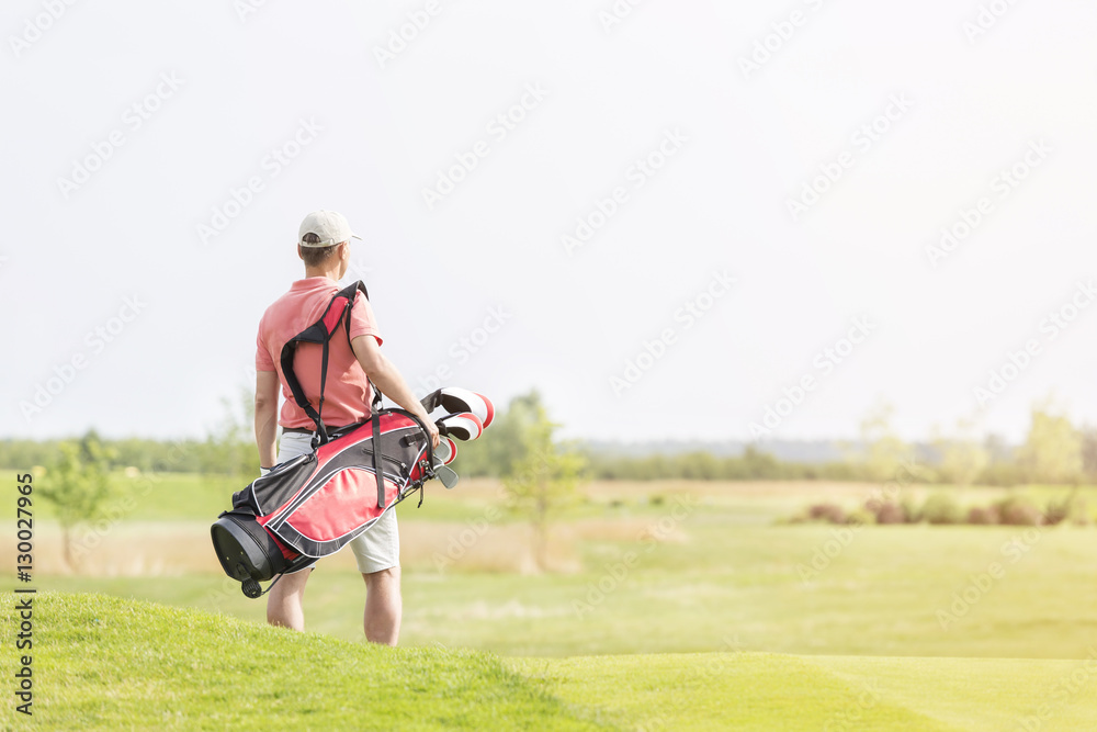 Rear view of man carrying golf club bag while walking at course Rear view of man carrying golf club bag while walking at course