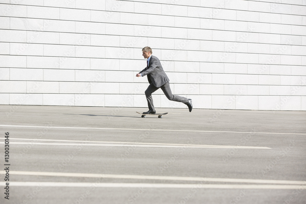 Side view of businessman skateboarding on street Side view of businessman skateboarding on street
