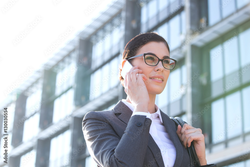 Low angle view of businesswoman using cell phone outside office building Low angle view of businesswoman using cell phone outside office building