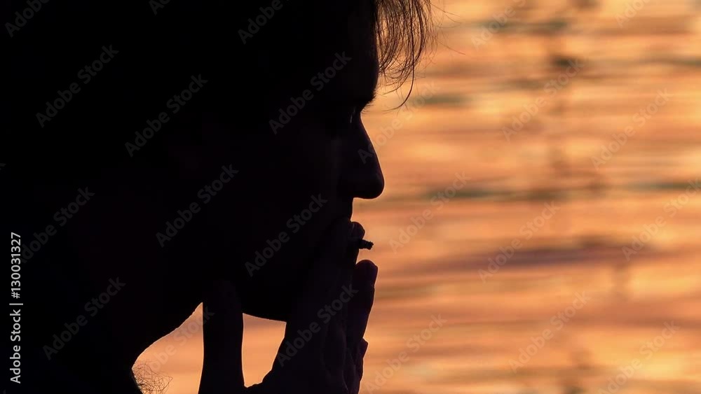 man smoking with water at the sunset in background man smoking with water at the sunset in background