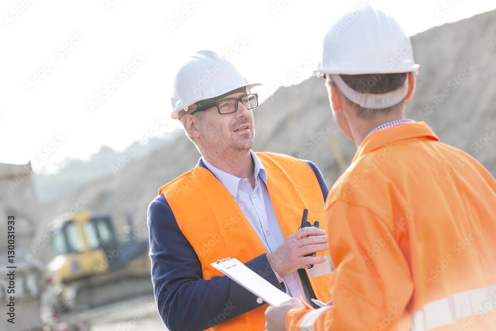 Architects discussing at construction site on sunny day Architects discussing at construction site on sunny day