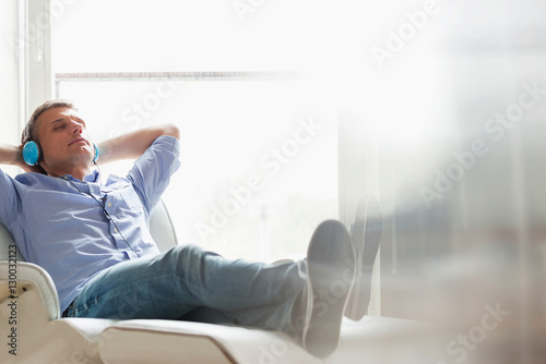 Full-length of relaxed Middle-aged man listening to music at home