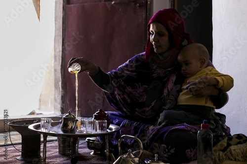 Saharawi woman preparing tea with her baby, Tindouf, Algeria