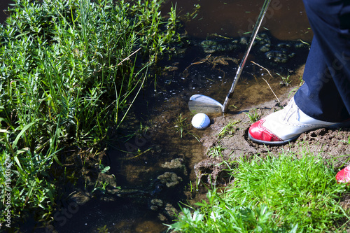 Man chipping ball from water hazard photo