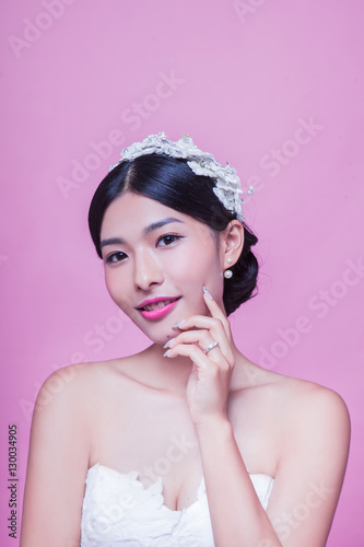 Portrait of beautiful bride with hand on chin against pink background