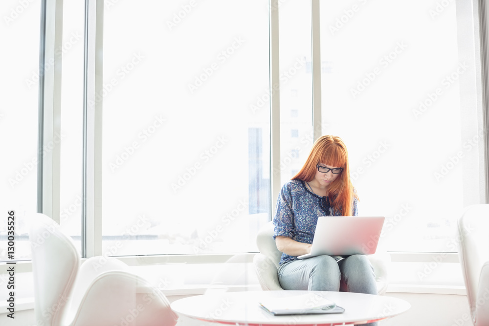 Young businesswoman using laptop in creative office Young businesswoman using laptop in creative office