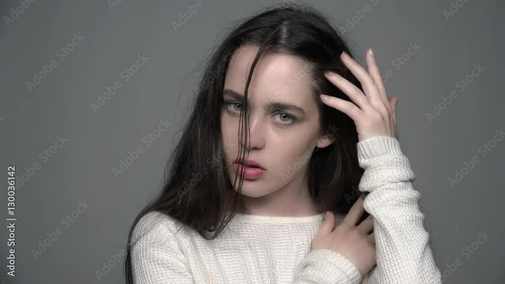 Slow motion video portrait of beauty young brunette woman portrait with green eyes in white fashion female pullover on gray background Slow motion video portrait of beauty young brunette woman portrait with green eyes in white fashion female pullover on gray background