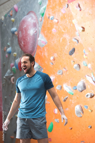 Dedicated man shouting by climbing wall in crossfit gym