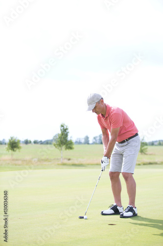 Full-length of middle-aged man playing golf at course