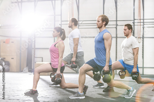 Determined people lifting kettlebells at crossfit gym