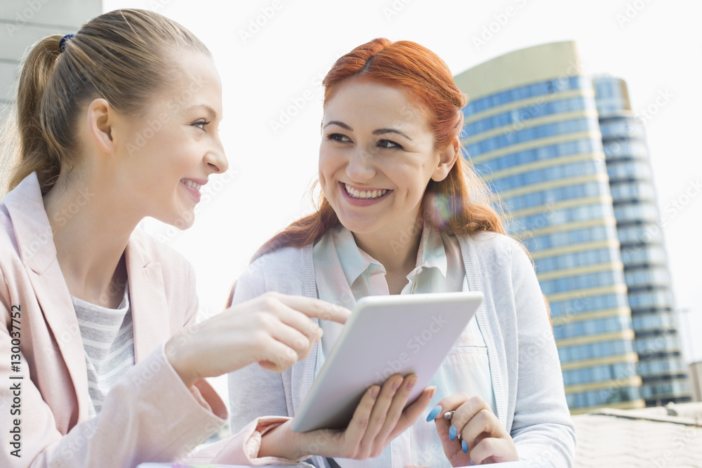 Smiling young university students using tablet PC against building Smiling young university students using tablet PC against building