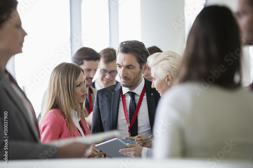 Business people discussing over digital tablet in convention center