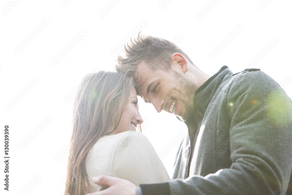 Smiling young man and woman embracing against clear sky Smiling young man and woman embracing against clear sky