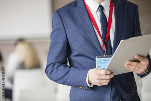 Midsection of businessman holding clipboard in seminar hall photo