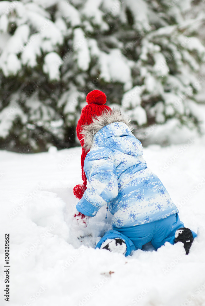 Little girl in the winter suit sitting on his knees in the snow Little girl in the winter suit sitting on his knees in the snow