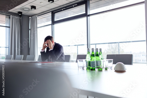 Mature businessman suffering from headache at conference table © moodboard